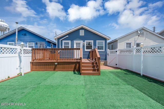 back of property with a wooden deck and a lawn