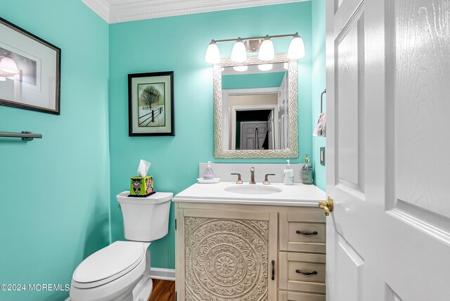 bathroom with crown molding, vanity, toilet, and hardwood / wood-style floors