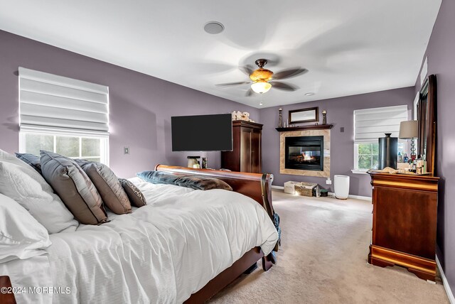 bedroom with ceiling fan, a tile fireplace, and carpet