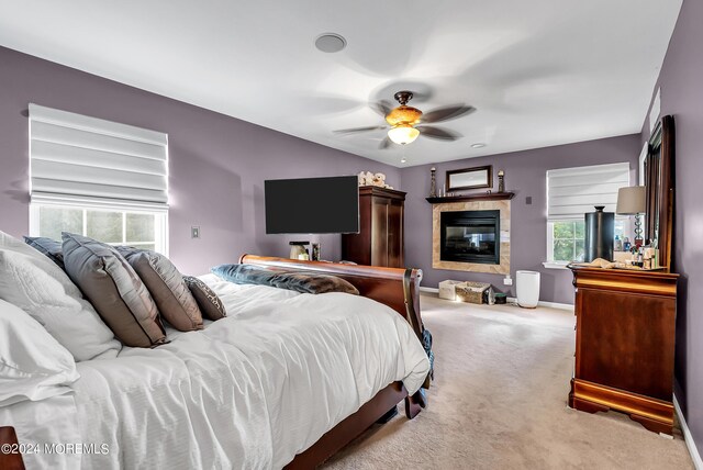 carpeted bedroom with ceiling fan and a fireplace