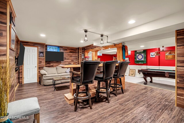 game room featuring hardwood / wood-style flooring, wood walls, pool table, and indoor bar