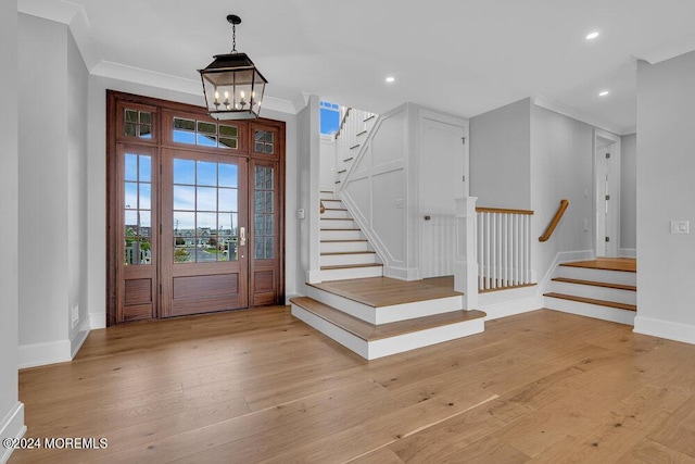 foyer with a notable chandelier, light hardwood / wood-style flooring, and crown molding