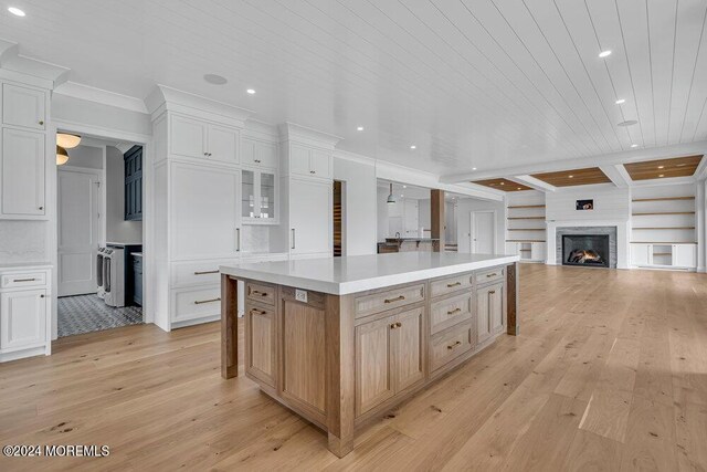 kitchen with light wood-type flooring, beamed ceiling, a center island, white cabinets, and wooden ceiling