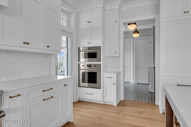 kitchen with light hardwood / wood-style flooring, white cabinetry, double oven, and tasteful backsplash