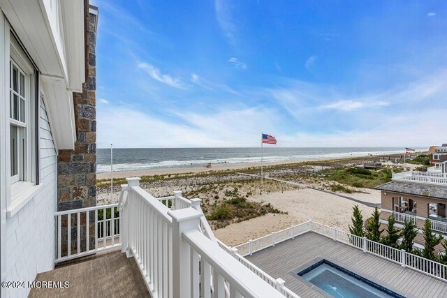 balcony featuring a water view and a beach view