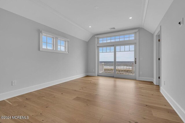 spare room featuring lofted ceiling and light hardwood / wood-style floors