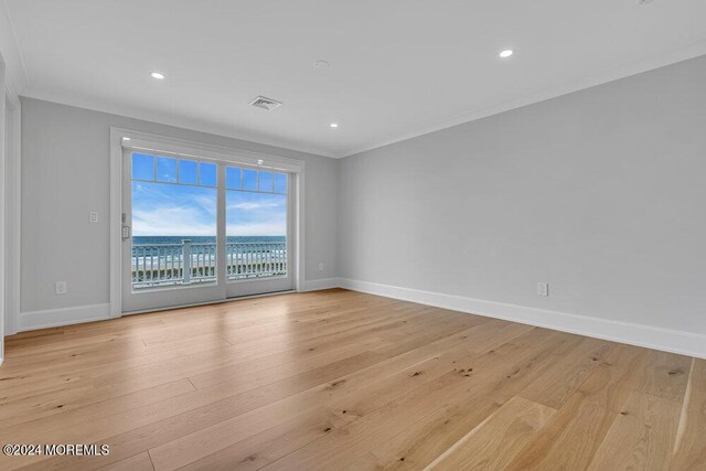 spare room with light wood-type flooring and crown molding