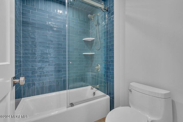 bathroom with enclosed tub / shower combo and toilet