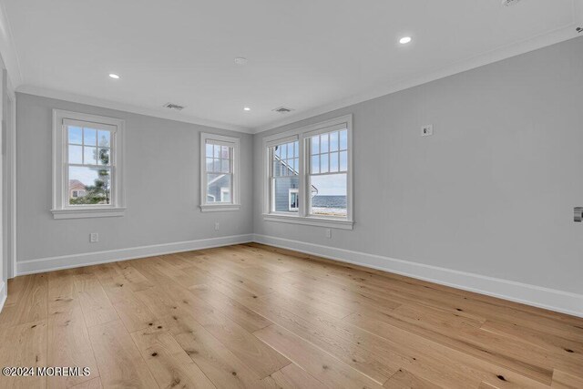 spare room featuring light hardwood / wood-style flooring, a wealth of natural light, and crown molding