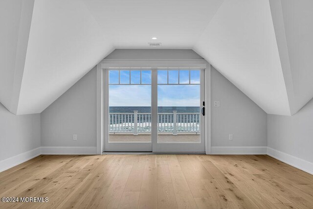 bonus room featuring light hardwood / wood-style floors, lofted ceiling, and a water view