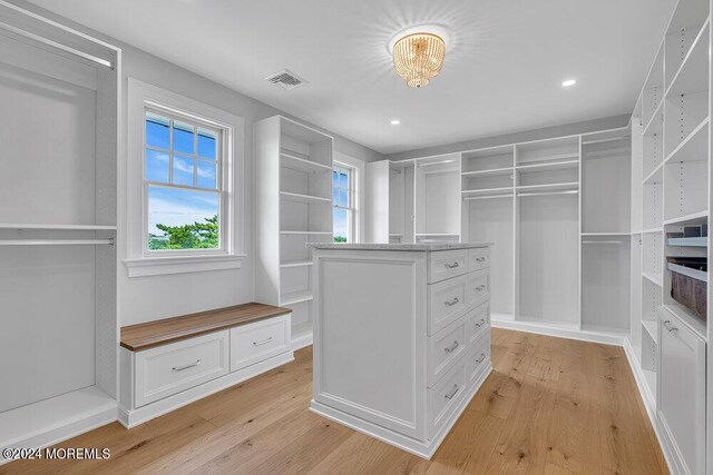 spacious closet with a notable chandelier and light wood-type flooring