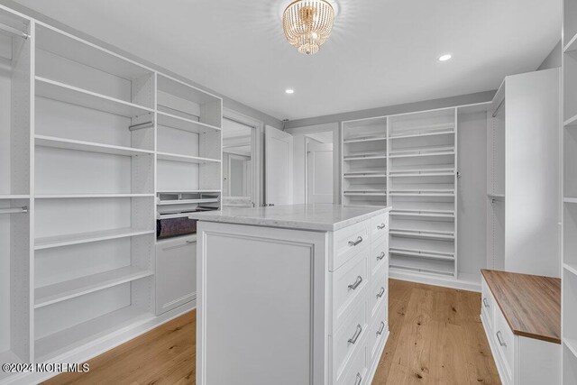 walk in closet featuring light hardwood / wood-style flooring and a notable chandelier