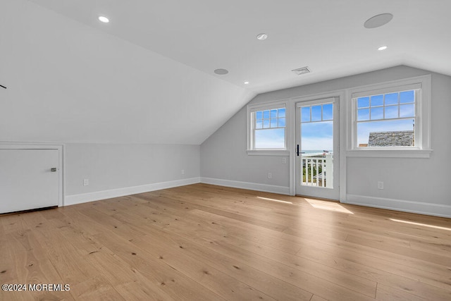 additional living space with light hardwood / wood-style floors and vaulted ceiling