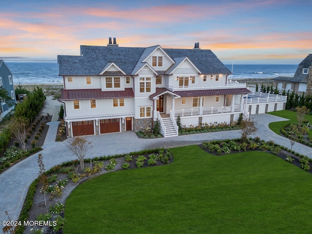 view of front of home featuring a garage, a yard, and a water view