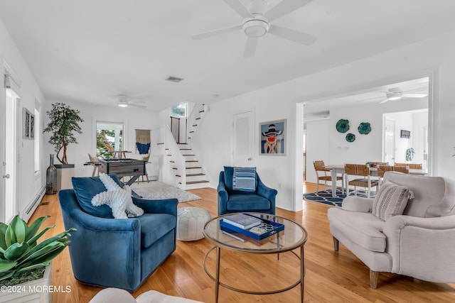 living room with a baseboard heating unit, ceiling fan, and wood-type flooring