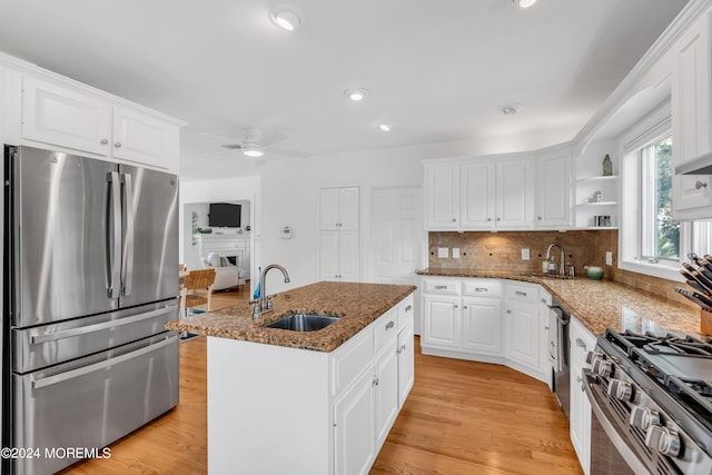 kitchen with white cabinetry, stainless steel appliances, an island with sink, ceiling fan, and sink