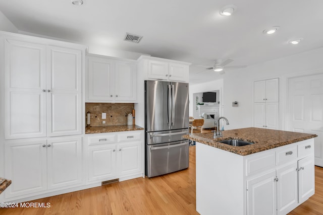 kitchen featuring light wood-type flooring, sink, stainless steel fridge, ceiling fan, and a kitchen island with sink