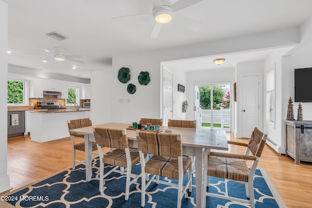 dining space with light wood-type flooring, a baseboard heating unit, and ceiling fan