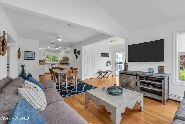 living room with ceiling fan, plenty of natural light, light hardwood / wood-style floors, and vaulted ceiling