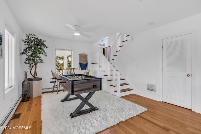 game room featuring a baseboard heating unit, ceiling fan, and light hardwood / wood-style floors