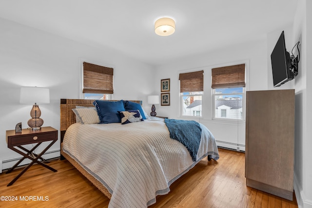 bedroom featuring a baseboard heating unit and wood-type flooring