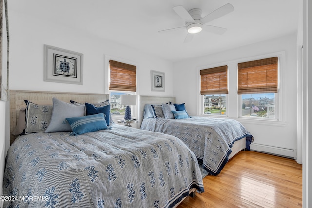 bedroom with light wood-type flooring, ceiling fan, and baseboard heating