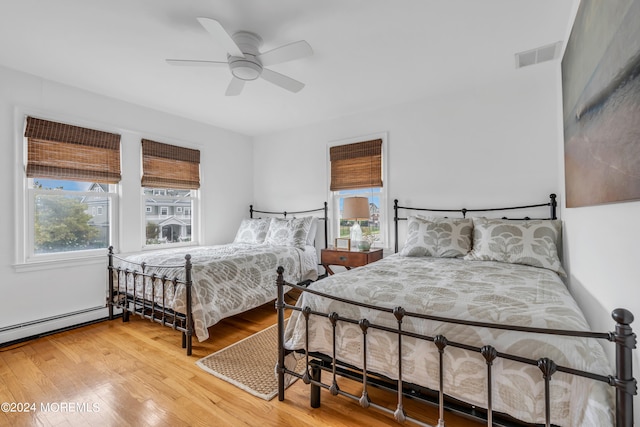 bedroom with ceiling fan, a baseboard radiator, and light hardwood / wood-style floors