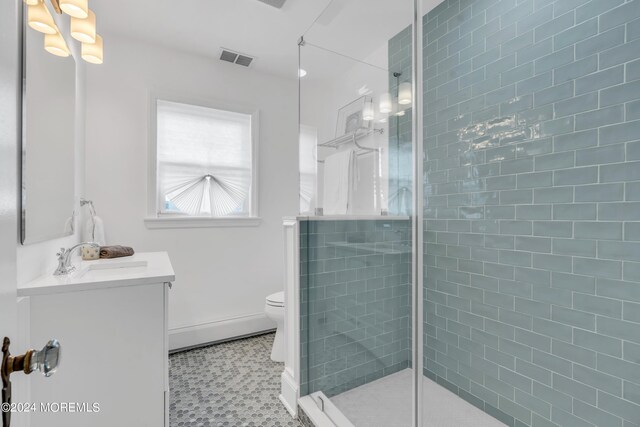 bathroom with a shower with door, vanity, toilet, and tile patterned flooring