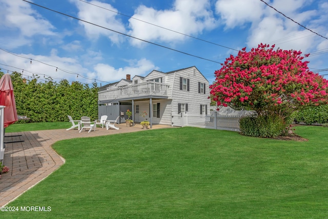 rear view of property with a balcony, a yard, and a patio