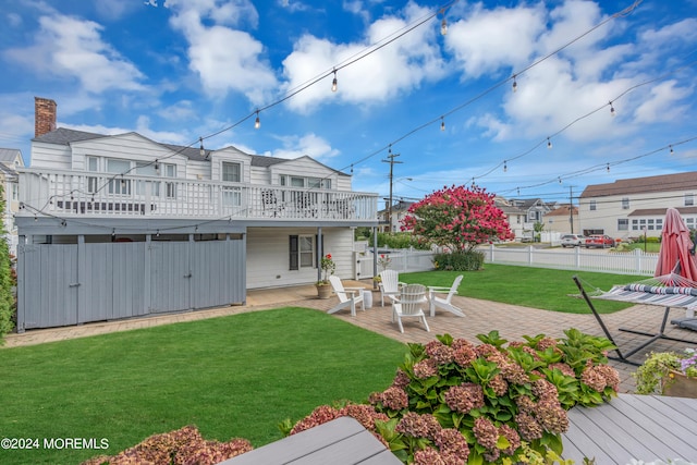 back of property with a wooden deck, a lawn, and a patio