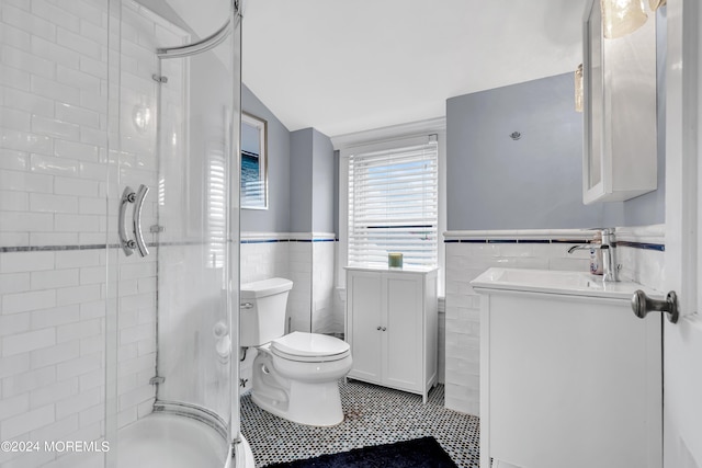 bathroom featuring tile patterned flooring, a shower with door, toilet, tile walls, and vanity