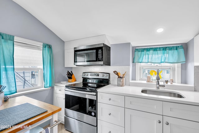 kitchen featuring a healthy amount of sunlight, stainless steel appliances, sink, and white cabinetry