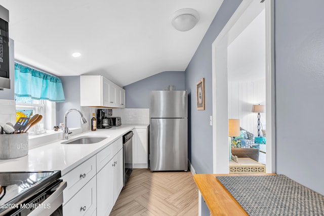 kitchen with appliances with stainless steel finishes, a healthy amount of sunlight, sink, and white cabinets