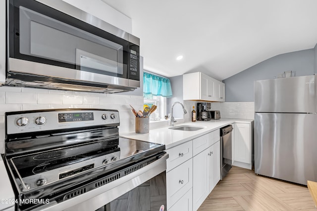 kitchen with stainless steel appliances, sink, decorative backsplash, lofted ceiling, and white cabinets