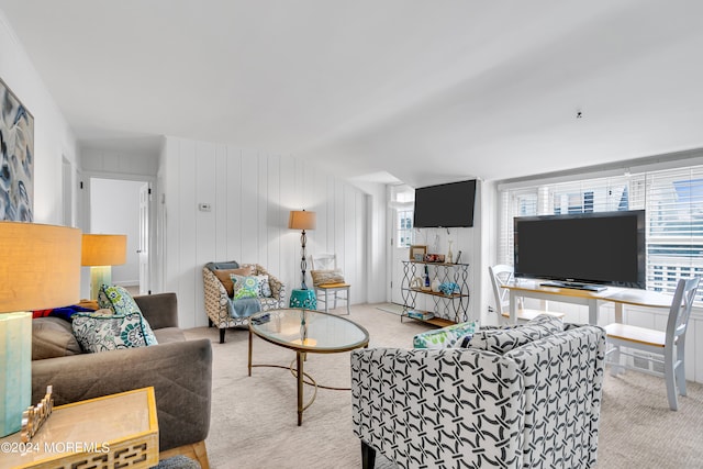 living room featuring light colored carpet and wooden walls