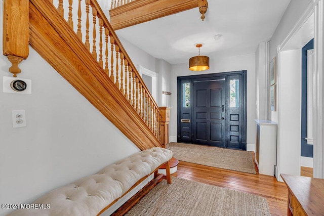 foyer entrance with stairs, hardwood / wood-style flooring, and baseboards