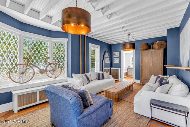 living room featuring beamed ceiling, radiator, wood finished floors, and baseboards