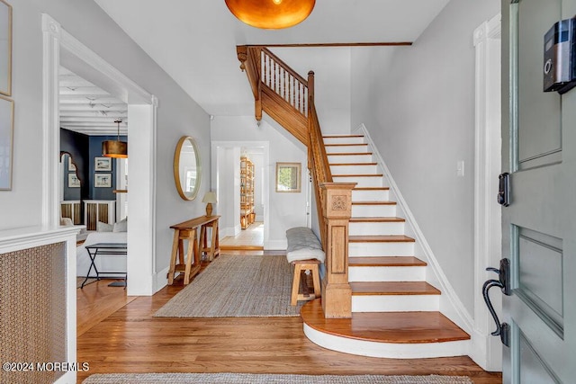 foyer entrance with stairs, baseboards, and wood finished floors