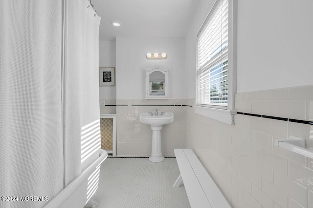 full bathroom with tile patterned flooring, tile walls, and a wainscoted wall