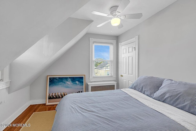 bedroom with lofted ceiling, a ceiling fan, wood finished floors, a closet, and baseboards