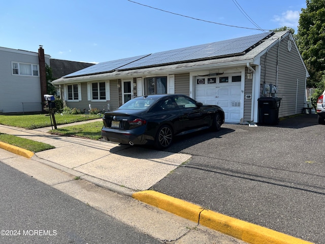 ranch-style home featuring a garage, solar panels, and a front yard