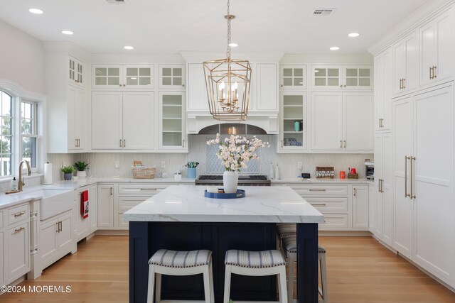 kitchen featuring light wood-type flooring, a notable chandelier, a center island, and sink