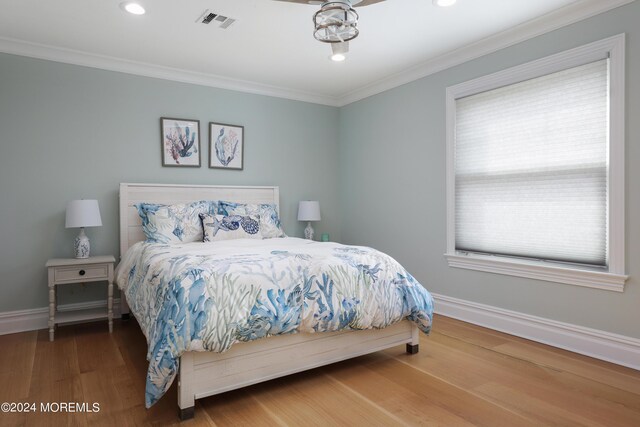 bedroom with ornamental molding, wood-type flooring, and multiple windows