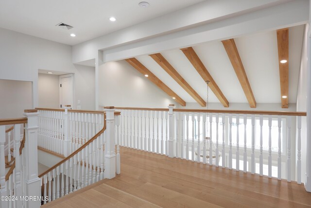 corridor with light hardwood / wood-style flooring and lofted ceiling with beams