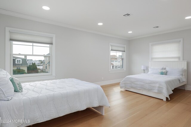 bedroom with ornamental molding and light hardwood / wood-style flooring