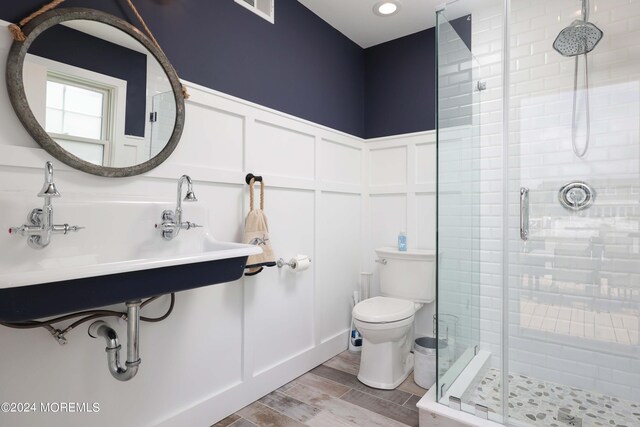 bathroom with toilet, wood-type flooring, and a shower with door