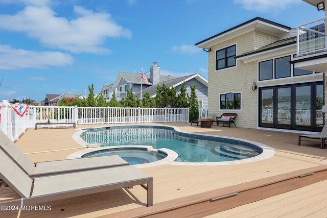 view of swimming pool featuring a wooden deck and an in ground hot tub