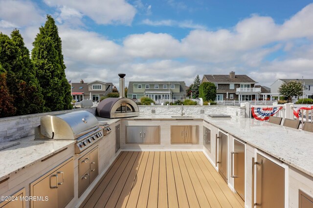 wooden terrace featuring grilling area and an outdoor kitchen