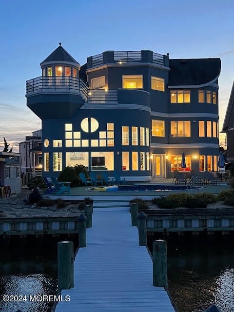 back house at dusk with a balcony and a water view