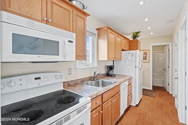 kitchen featuring light countertops, recessed lighting, light wood-style floors, white appliances, and a sink